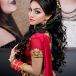 A beautiful woman in traditional attire elegantly poses, showcasing intricate designs and vibrant colors.